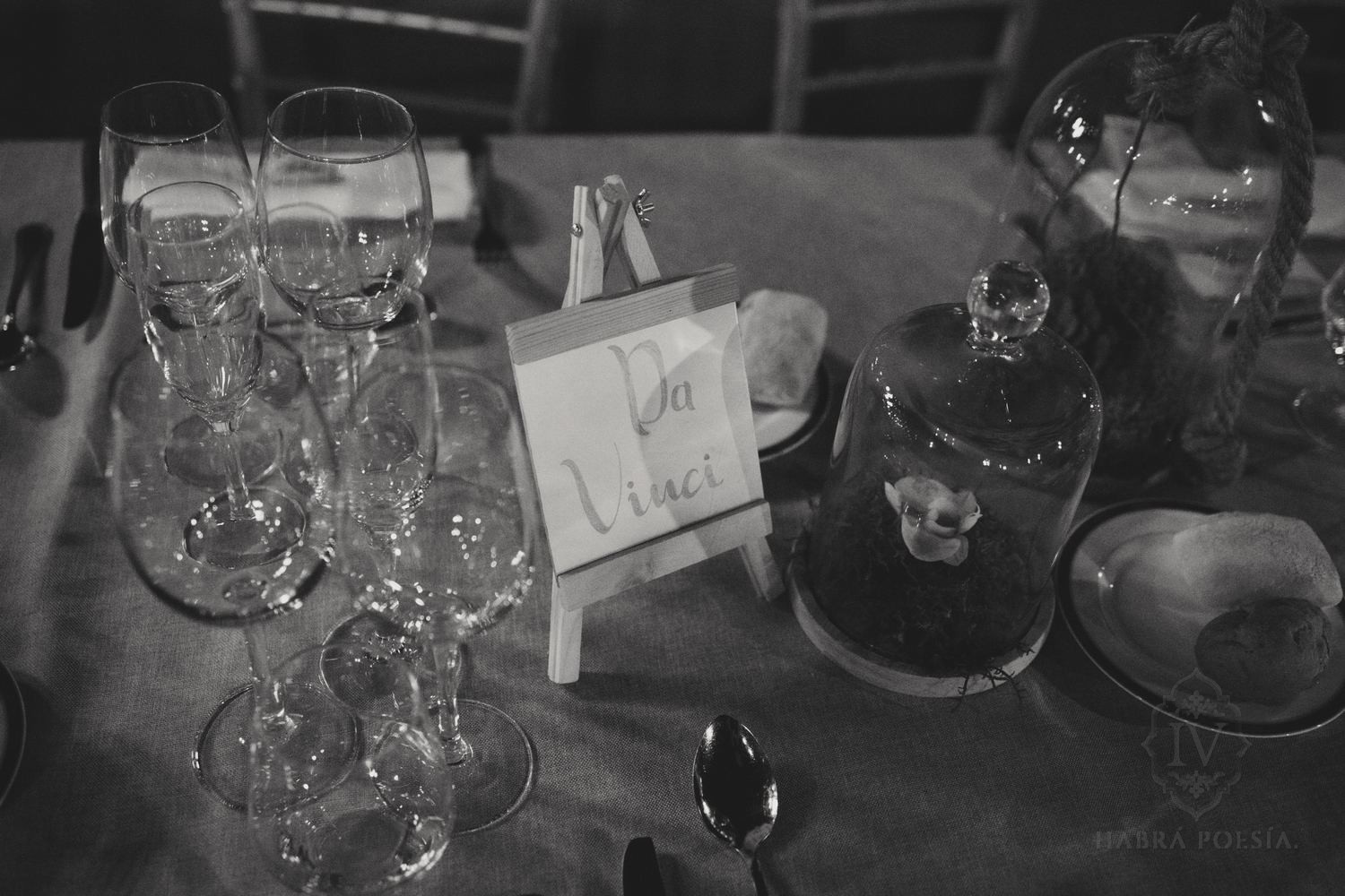 Detalle de mesa de boda con copas y cartel de mesa, en blanco y negro