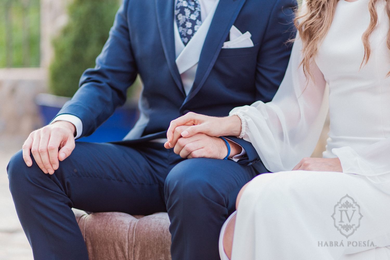 Novios cogidos de la mano durante la ceremonia, él con traje azul