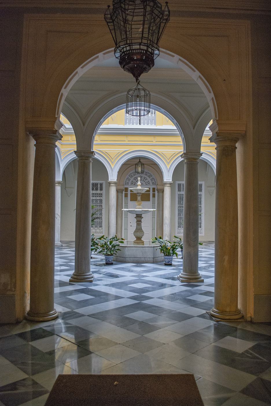 Patio andaluz con arcos, farol y suelo de mármol
